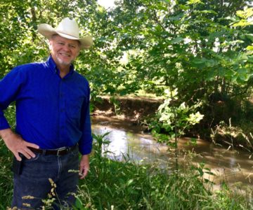 Bobby Whitescarver smiles next to a mature riparian forest buffer