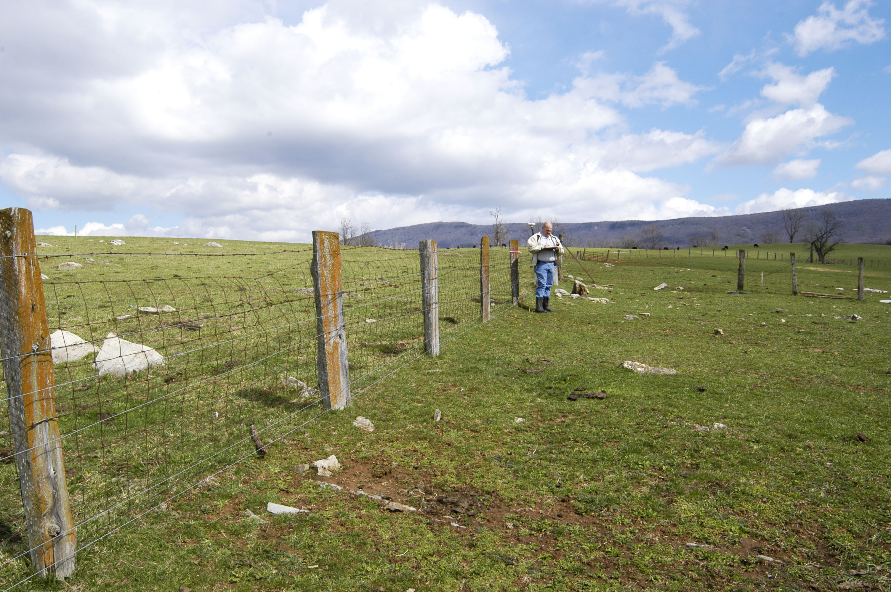 A farmer surveys his land and measures a length of fence for buffer planting as part of the CREP program.